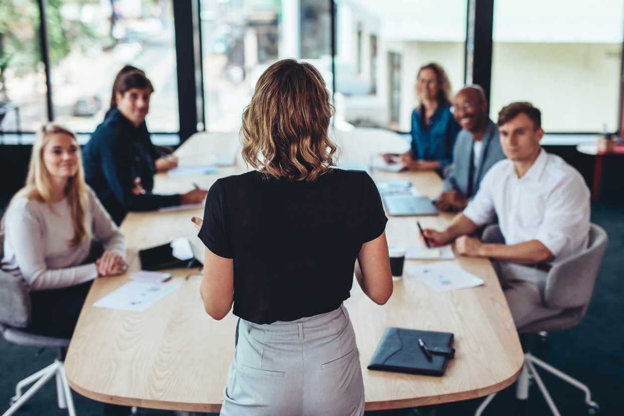 Rear view of a businesswoman addressing a meeting in office. Female manager having a meeting with her team in office boardroom.