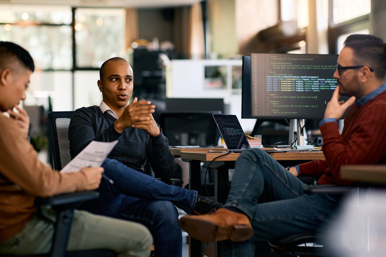 African American IT engineer and his colleagues communicating on a meeting in the office.