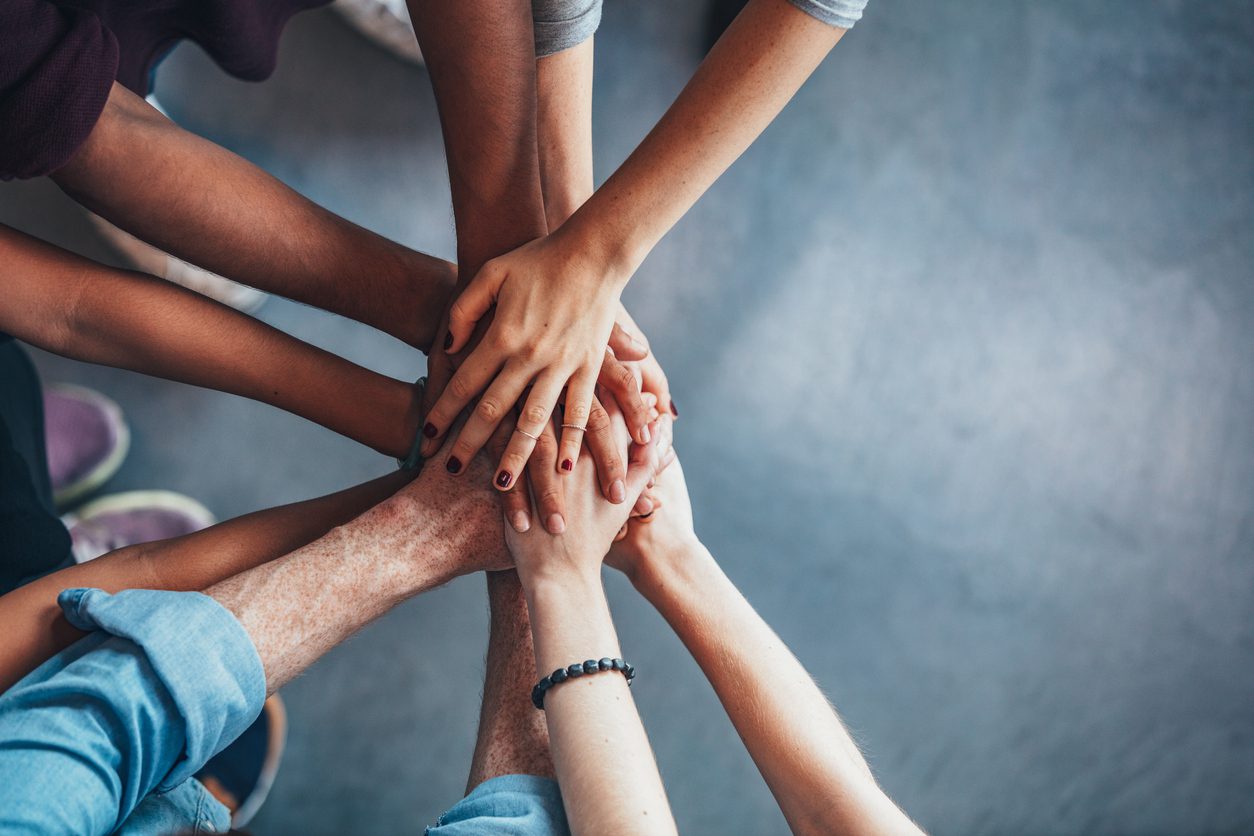 Close up top view of young people putting their hands together. Friends with stack of hands showing unity.